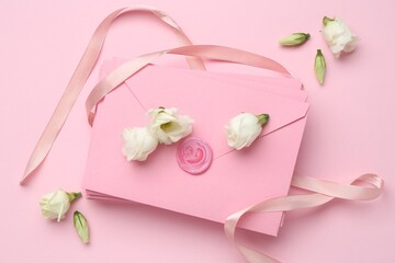 Stack of love letters, ribbon and flowers on pink background, flat lay