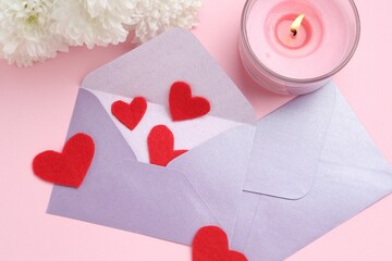 Love letters, red hearts, burning candle and flowers on pink background, flat lay