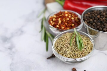 Different aromatic spices on white marble table, closeup. Space for text