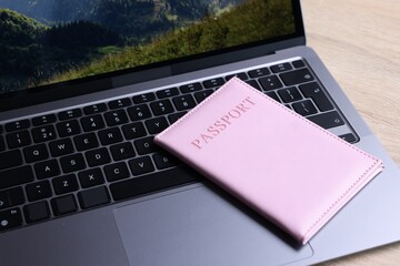 Passport and laptop on light wooden table, closeup