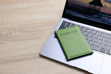 Passport and laptop on light wooden table, closeup. Space for text