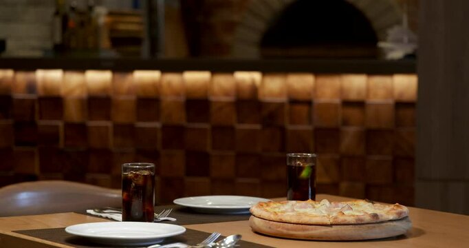 Pizza and drinks on restaurant table, cozy dining scene in rustic pizzeria with wood oven background. Italian cuisine, casual dining, food in restaurant.