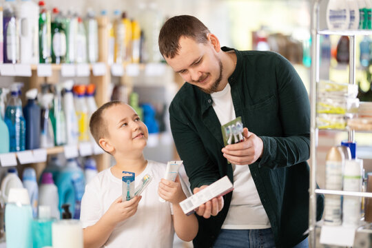 Young man with boy shoppers buying toothbrush in household chemicals store