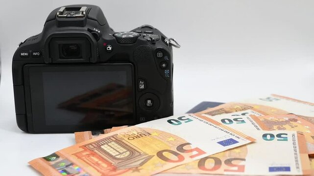 billes de euro cayendo sobre una camara y un pasaporte en fondo blanco