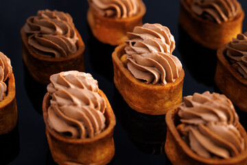 Caramel tartlet, caramelized peanuts, salted caramel, chocolate ganache. Dessert of dough, nut tartlets covered with a layer of caramel. Tartlet with caramelized nuts isolated on black. Tasty dessert