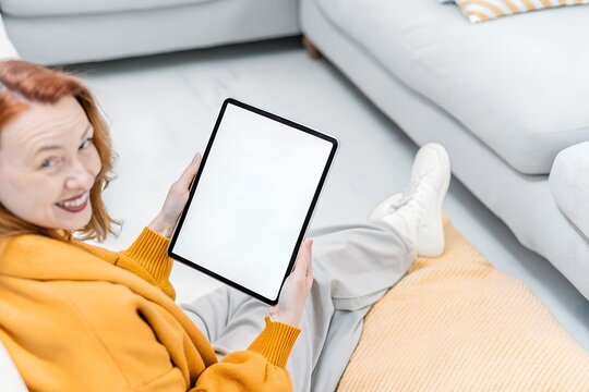 Happy cute simple smile baby girl ,women and old women using online food delivery app on tablet at home, sitting on the floor in a bright and modern living room, showing the blanc screen