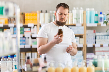 Male shopper carefully reads the name of cough syrup on the label