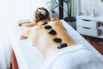 Hot stone massage at spa salon in luxury resort with day light serenity ambient, blissful woman...
