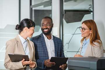 multicultural female and male colleagues stand by the copy machine