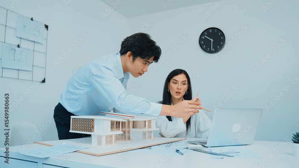 Poster professional male asian architect using ruler to measure house model length while young beautiful ca