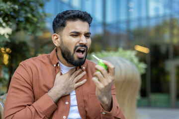 A man uses throat spray to soothe his throat and possibly treat angina, with a look of discomfort