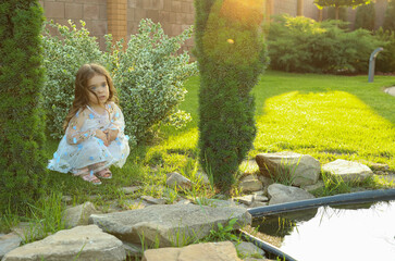  A little girl is sitting by the pond