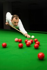Man concentrating on precise shot during snooker game in dimly lit room