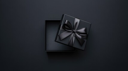 Open black gift box with black ribbon on dark background