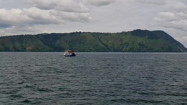 View of the KMP Pora pora ferry sailing on Lake Toba with small waves. Domestic ferry with a fixed route on lake waters. Sailing from Samosir to Parapat and vice versa.