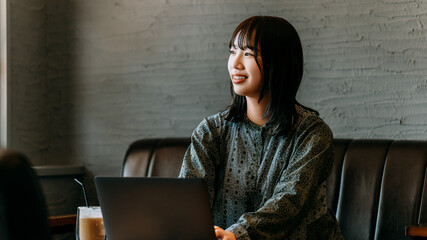 カフェでノートパソコンを使う若い女性