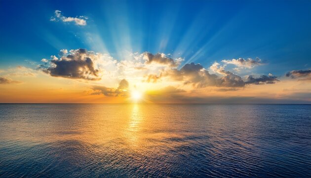 beautiful blue sky with a golden sunset and sun rays over the water