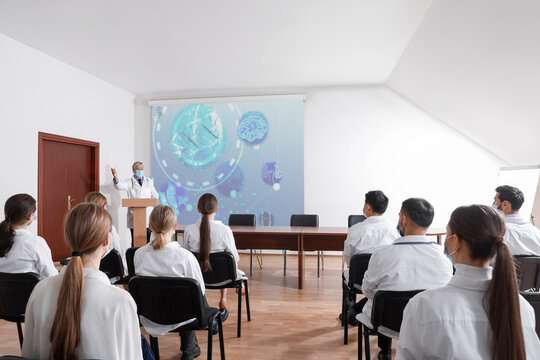 Healthcare professional giving lecture about DNA in conference room using video projector. Illustration on projection screen