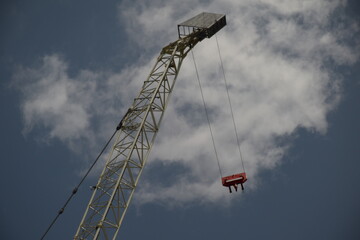crane with hanging cables seen from below with a partially cloudy sky in the background 