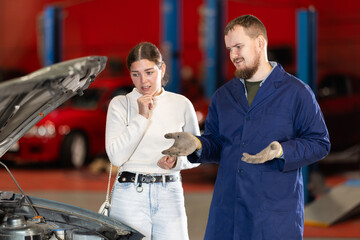 Auto mechanic checking young woman client car in car service center