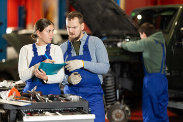 Car service employee fills out the documents and consults with the mechanic about the repair and...