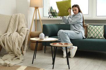 Emotional young woman with pillow looking in disgust at cockroaches on table at home