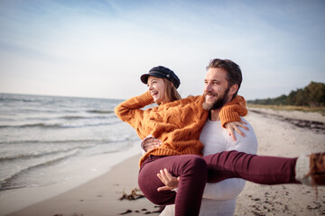 Romantic couple walking on the beach in cozy autumn sweaters