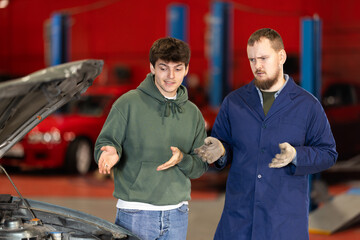 Guy discusses further repairs to his car with car mechanic at a car service center