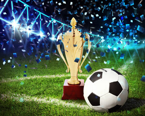 Football championship. Shiny golden trophy cup and soccer ball under falling confetti on stadium