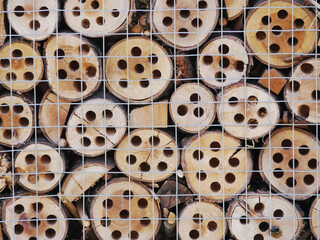 stack of slices of tree trunks with drilled holes put together for an insect hotel