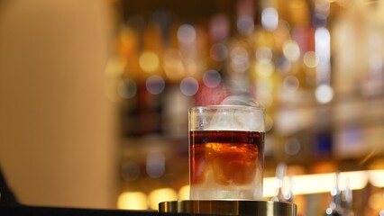 Focusing serving mist smoky classical in Old fashioned of whiskey cocktail presentation on bokeh...