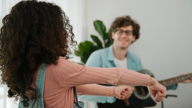 Attractive caucasian dad playing guitar while cute daughter dancing to music. Happy father and american girl spend time together while smart child move to music. Family recreation concept. Pedagogy.