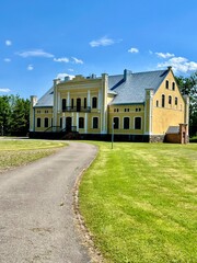 Obraz premium Historical Dauksiagire manor in Prienai district, Lithuania. Yellow manor house with classical architectural features, featuring a symmetrical facade and arched windows.