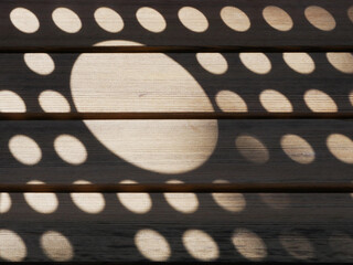 shadow pattern made of a mesh of different circles on a wooden board
