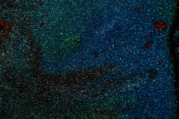 Macro shot of a glittering texture with dark base and tiny blue and red specks. Perfect as abstract...