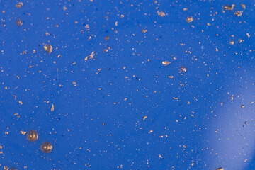 Close-up of a vivid blue surface covered with scattered metallic speckles and a subtle reflection in the corner.