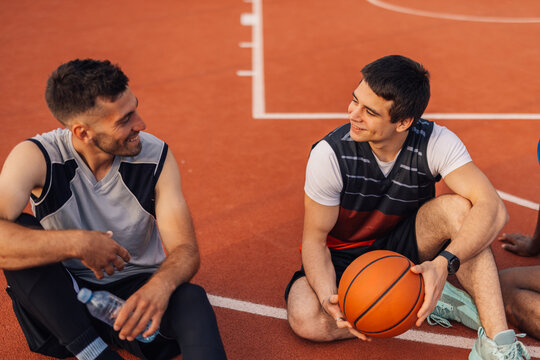 Two basketball players relaxing and chatting on court after game - Powered by Adobe