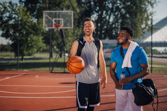 Two male basketball players talking and laughing on outdoor court
