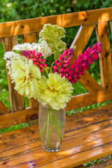 Bouquet of yellow peonies in a vase on a wooden bench