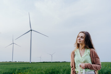 Young woman standing in field with wind turbines behind