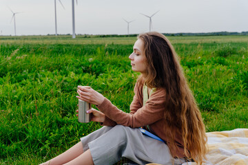 Woman resting in grass with closed eyes near wind turbines