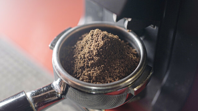 Coffee grinder grinds fresh coffee beans into a portafilter. Barista grind espresso coffee bean with grinder machine. Ambient light. Selective focus - Powered by Adobe