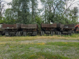 Old, rust-eaten trucks rest on a weed-choked wasteland, definitively out of service.