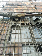 Old rusty windows with thick grille bars, covered in layers of dust and grime, create a grim atmosphere of an abandoned plant.