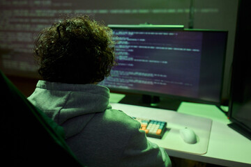 A young programmer codes intently in a dark setting, immersed in his work and creativity