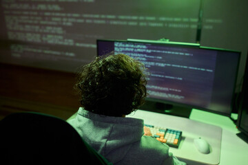 A young programmer codes intently in a dark setting, immersed in his work and creativity