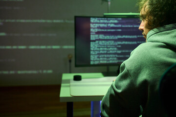 A young programmer codes intently in a dark setting, immersed in his work and creativity