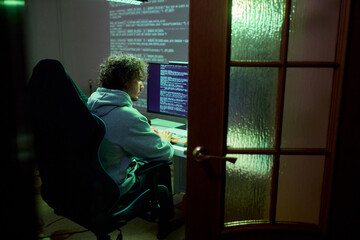 A young programmer codes intently in a dark setting, immersed in his work and creativity