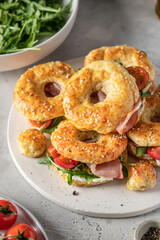 Homemade bagle sandwiches with ham, soft cheese and vegetables on whire board on kitchen table background. Homemade burgers