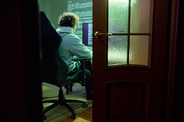 Fototapeta premium A Focused Individual is Working Late at a Computer in a Dimly Lit Room During Night Hours